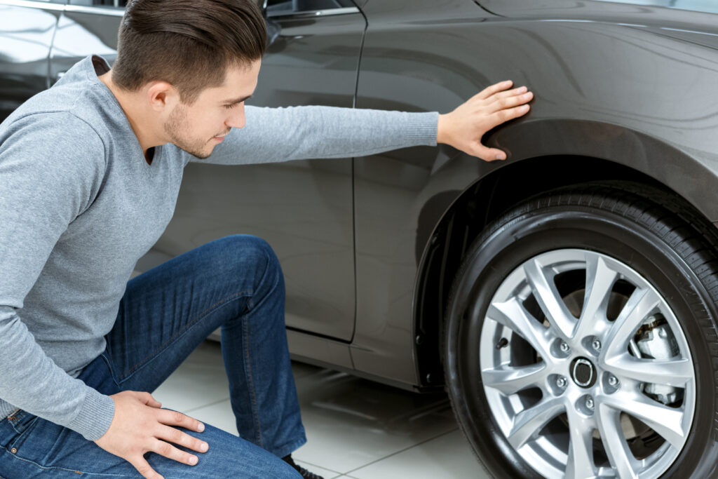 Final check. Horizontal portrait of a man checking tires on his new car